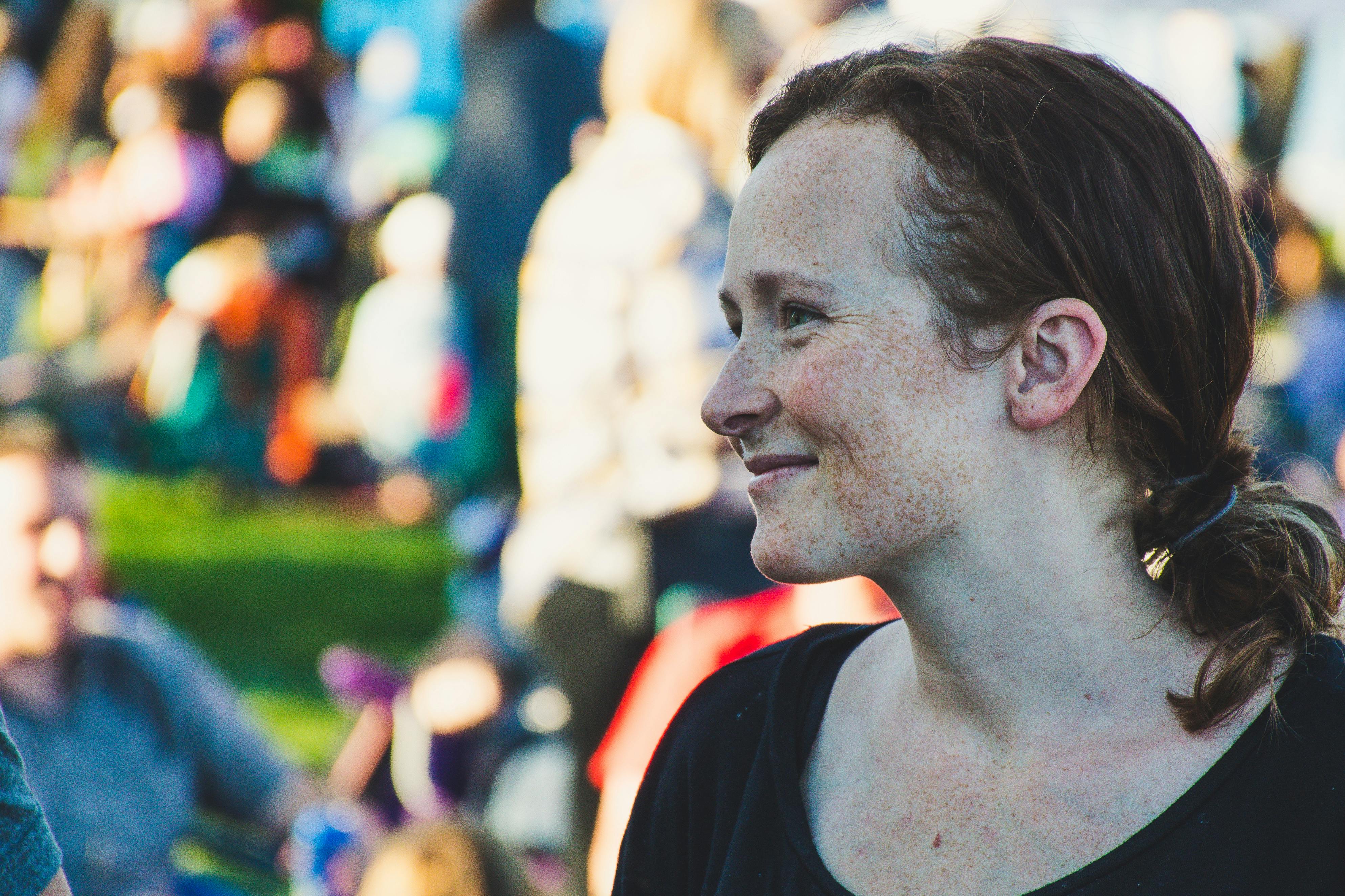 一名微笑女子的特写镜头，摄于白天户外节日的人群中