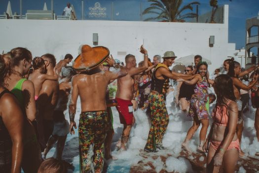 Energetic crowd enjoying an outdoor foam party, dancing and having fun in a lively atmosphere.