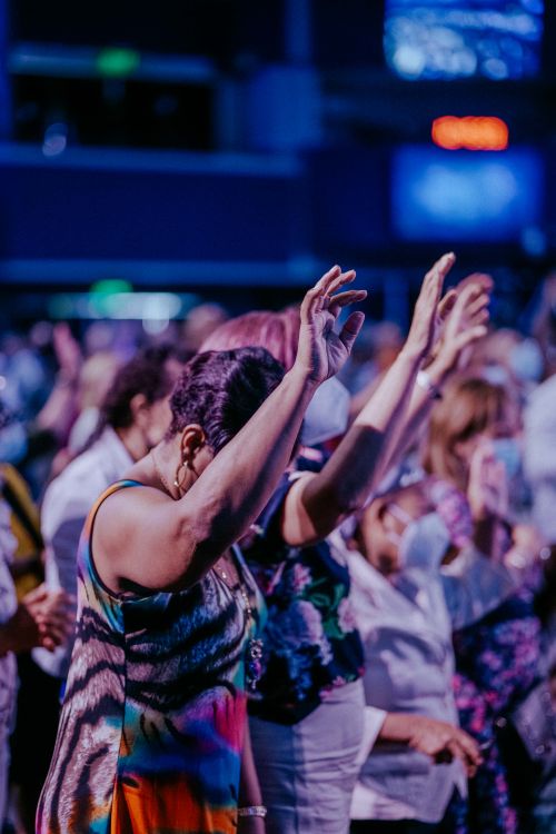 Free People raising hands in engaged worship at a dynamic indoor event. Stock Photo