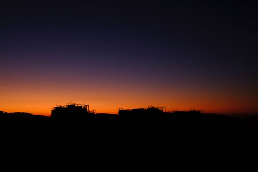 A city skyline silhouetted against a vibrant, colorful sunset sky.