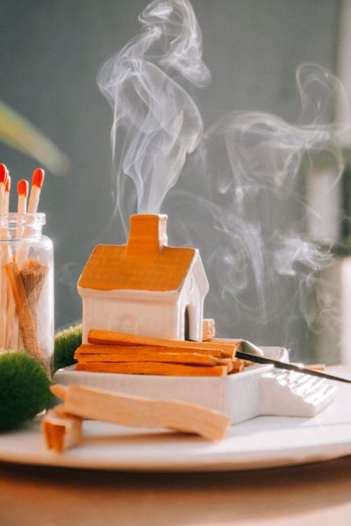 Free Miniature ceramic house incense burner emitting gentle smoke in a serene indoor setting. Stock Photo