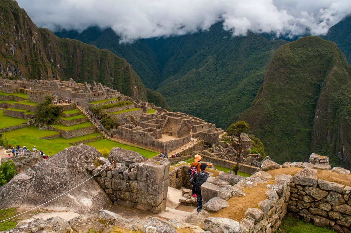 Breathtaking view of Machu Picchu amidst mountains, with tourists exploring the ancient Inca ruins.