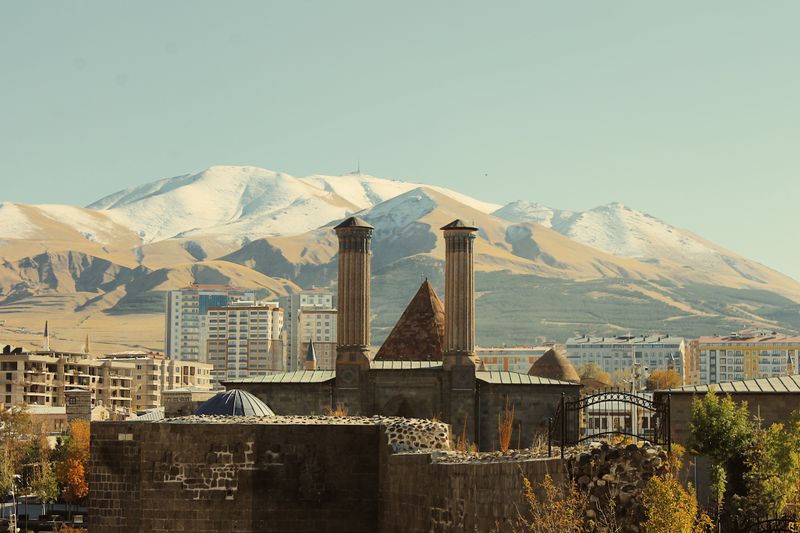 Erzurum'da karlı dağların önündeki tarihî Çifte Minareli Medrese
