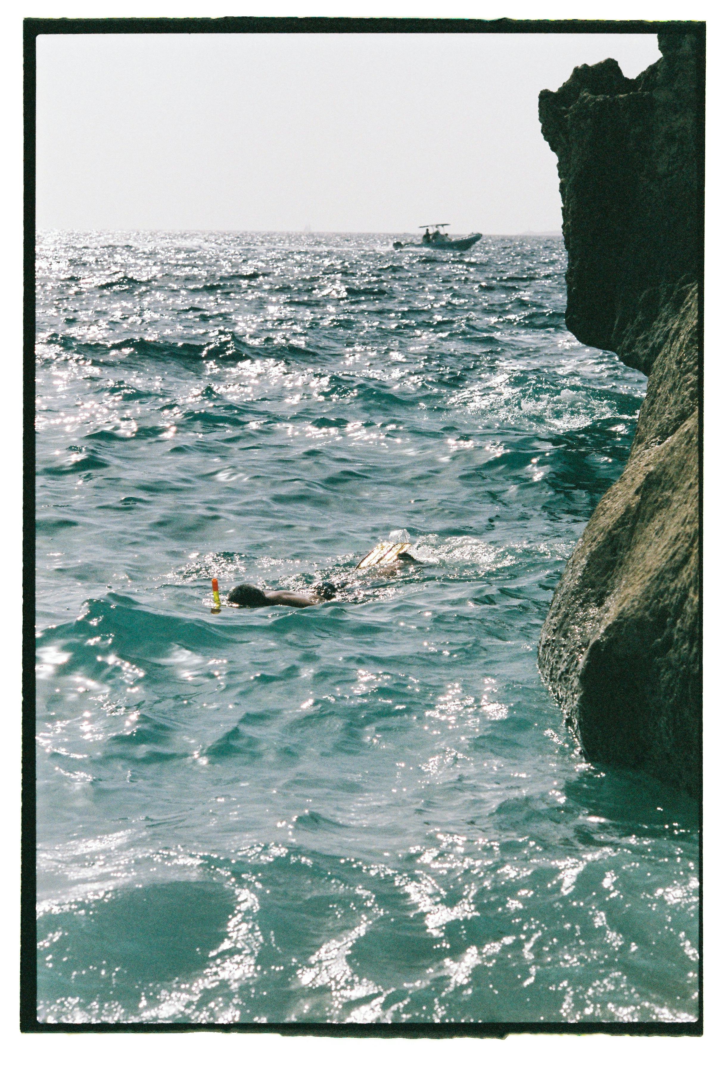person snorkeling near rock on shore