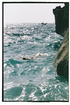 A person enjoys snorkeling in the clear waters off the rocky coast of Ibiza, Spain.