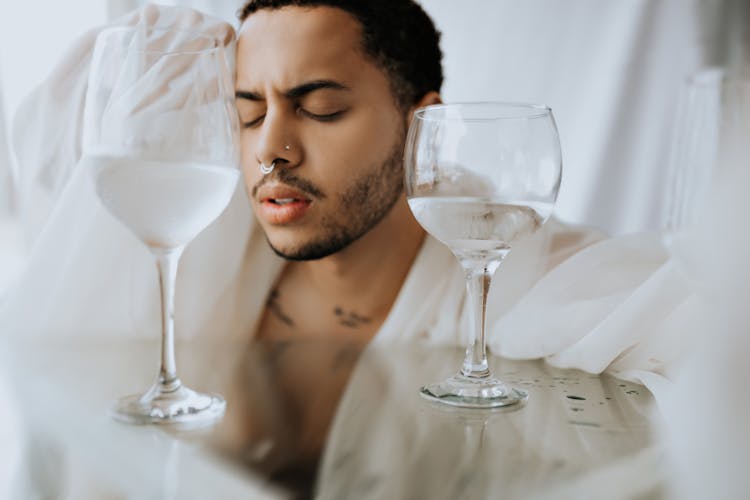 Man With Eyes Closed By Table With Water Glasses