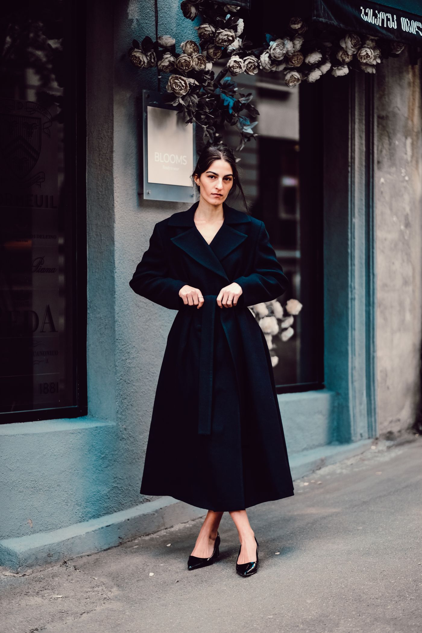 A woman in an elegant black velvet dress on a street sidewalk — understated evening minimalism