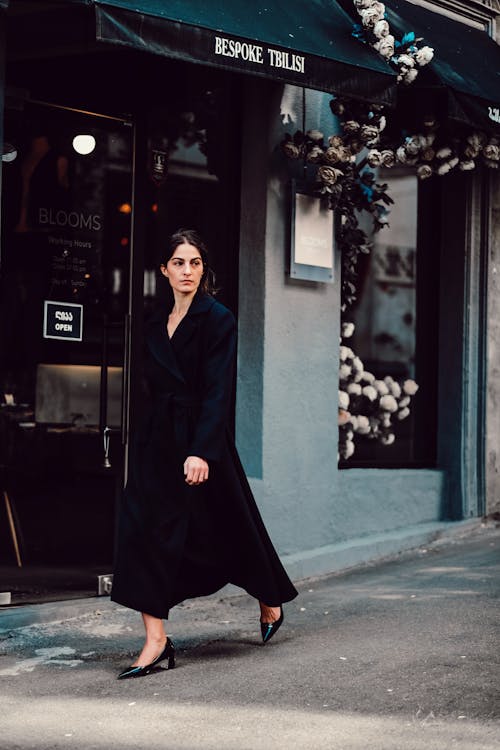 A Woman in a Black Coat Walking on a Street