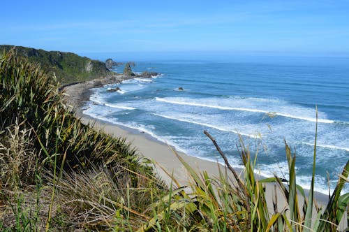 View From a Grassy Hill Overlooking a Sandy Beach