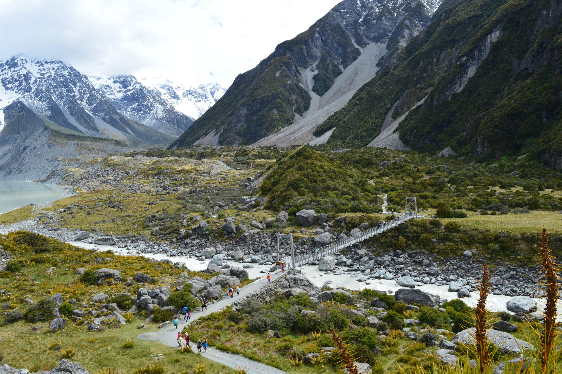 Hikers crossing a suspension swing bridge over a glacial river on the Hooker Valley Track in Aoraki/Mount Cook National Park