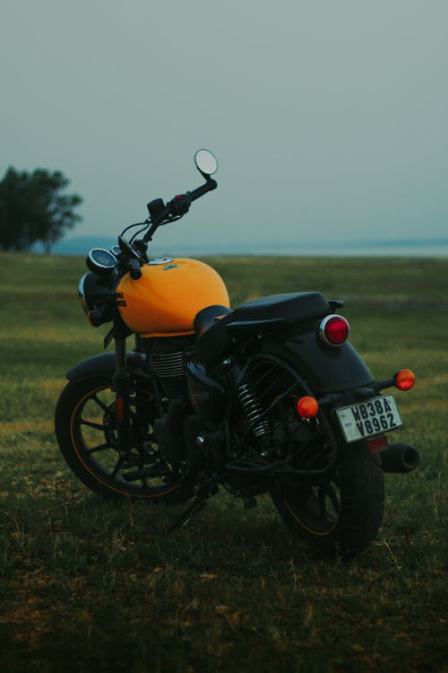 A Black and Yellow Motorcycle Parked on a Grass 