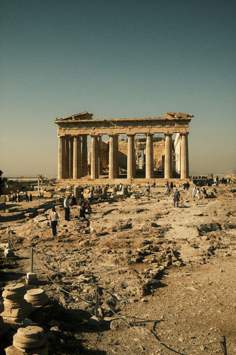 The Parthenon stands majestically in Athens under a clear sky, surrounded by ancient ruins.