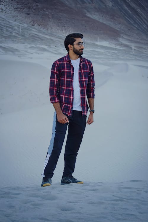 A Man in Red and Blue Plaid Long Sleeves Standing on Snow 