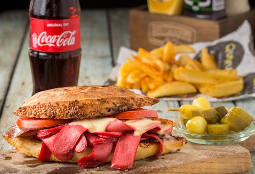 Mouth-watering sandwich with pickles and fries, served with Coca Cola in Sarıyer, Turkey.