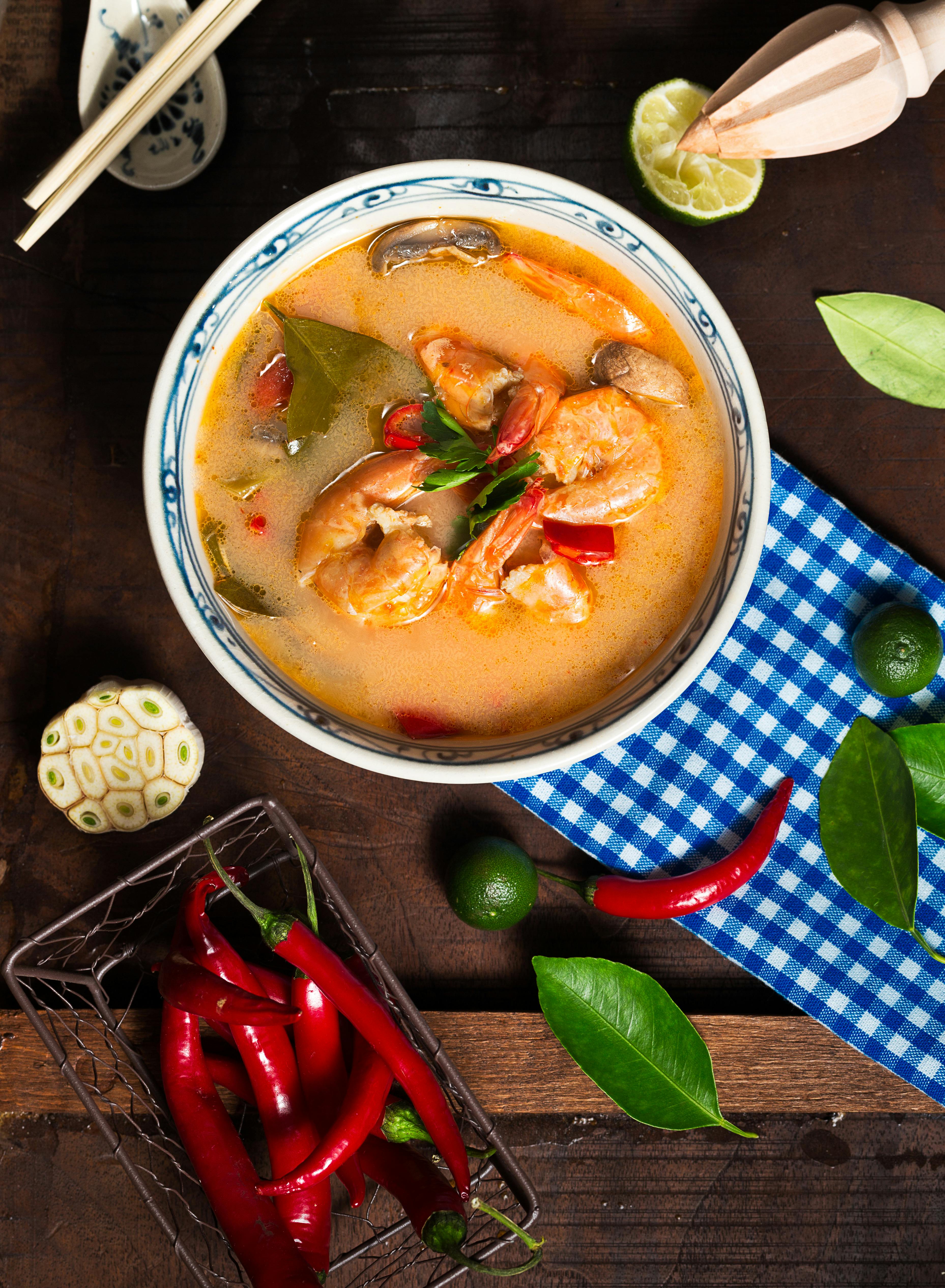 shrimp soup in white ceramic bowl with chili on brown wooden surface