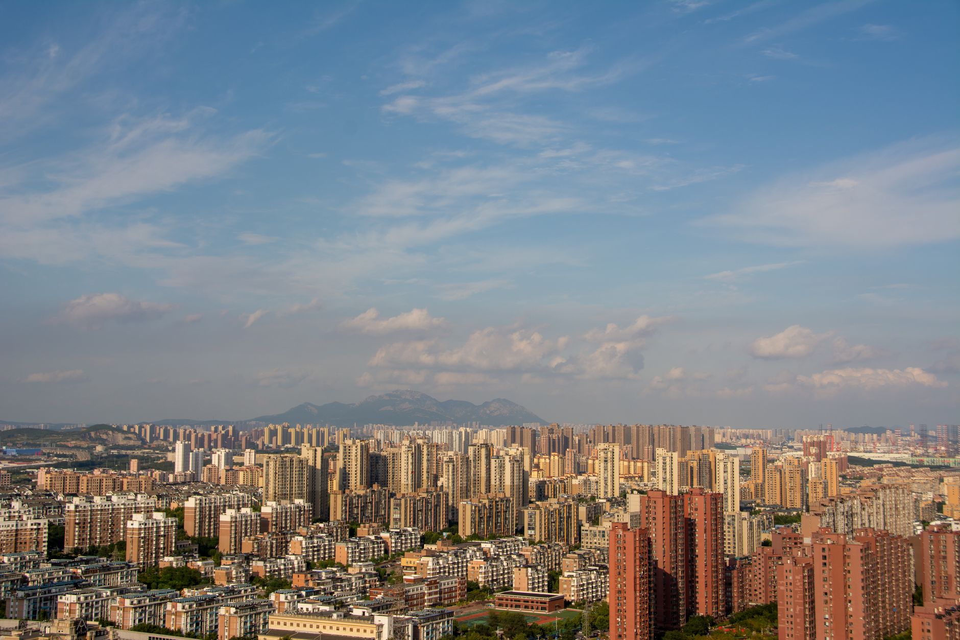 Aerial view of a sprawling urban cityscape with high-rise buildings under a clear blue sky.