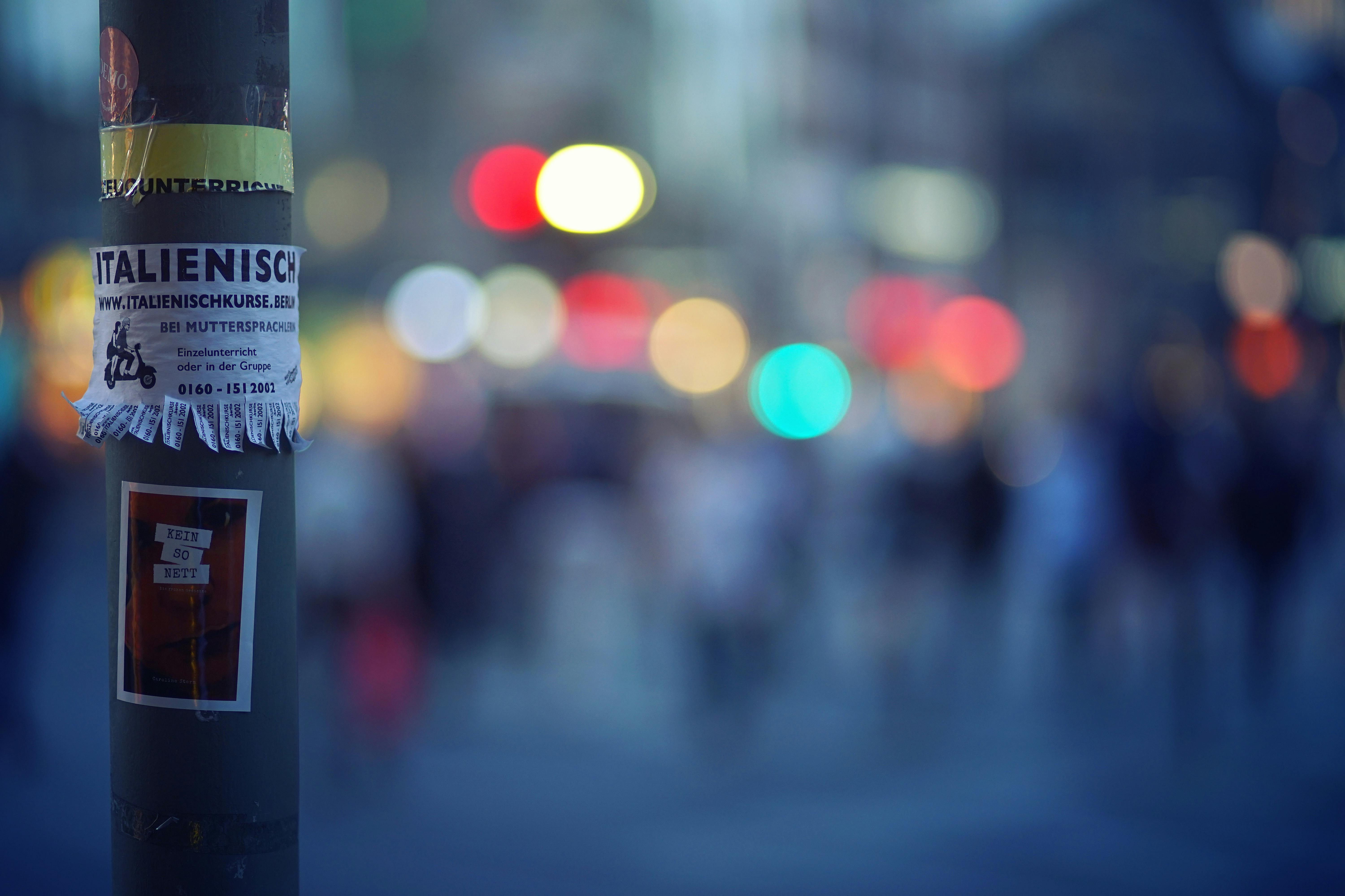 Colorful urban nightlife with bokeh lights and pole poster in foreground.