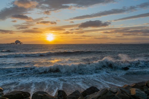 Free Ocean Waves Crashing on Rocky Shore During Sunset Stock Photo