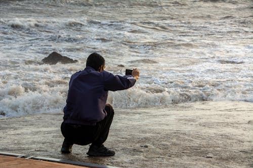 Man in Blue Jacket on Beach Shore