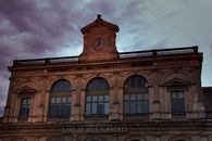 Majestic view of Gare de Lille Flandres clock tower under a dramatic sky.