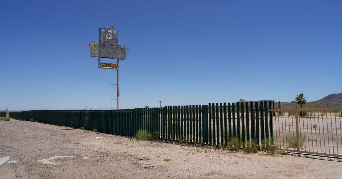 Old, abandoned lot with a weathered sign and fence in the Arizona desert.