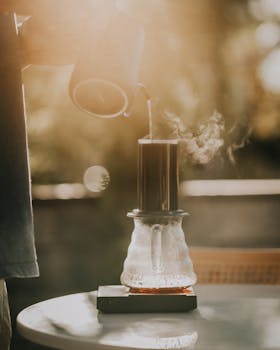 Pouring hot water into a coffee maker with steam rising, captured in warm sunlight.
