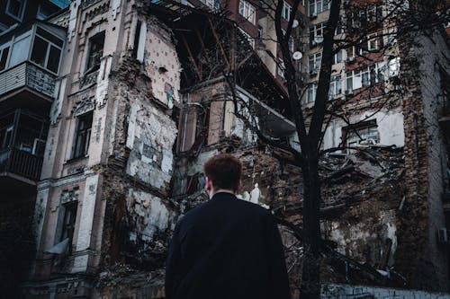 Man Standing Near Destroyed Concrete Building