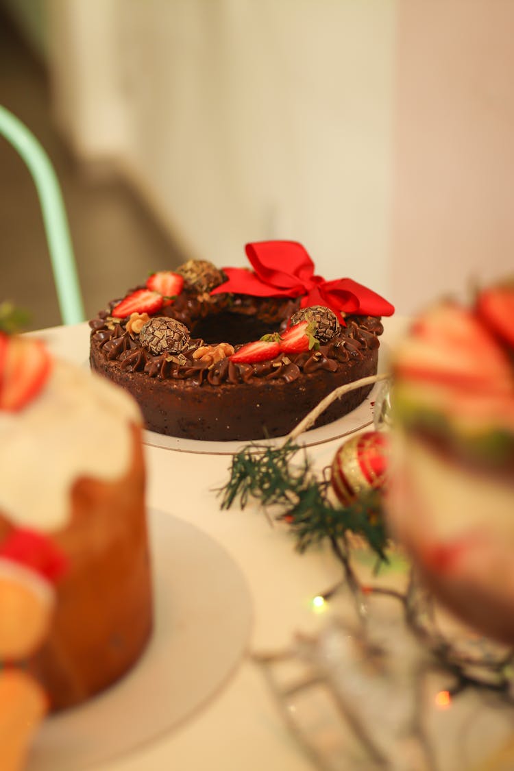 A Round Christmas Fruitcake With Red Ribbon Served On Table