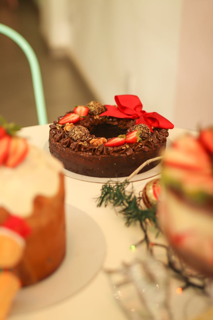 A Round Christmas Fruitcake With Red Ribbon Served On Table