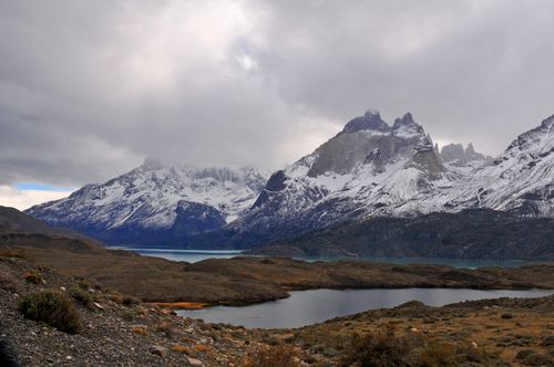 Free Breathtaking scene of snow-capped mountains and serene lake under cloudy skies. Stock Photo