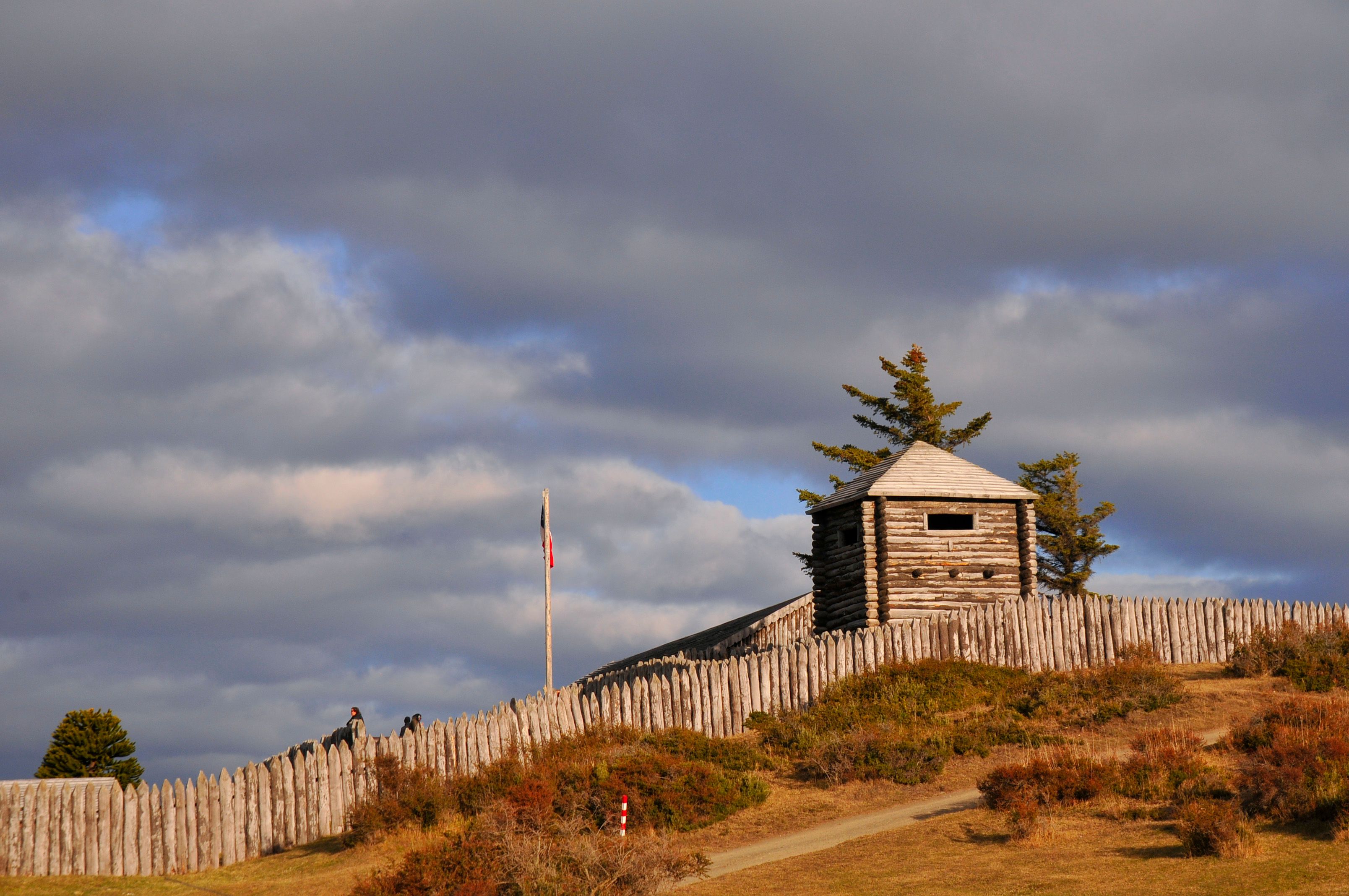 A reconstructed wooden stockade fort on a grassy hill