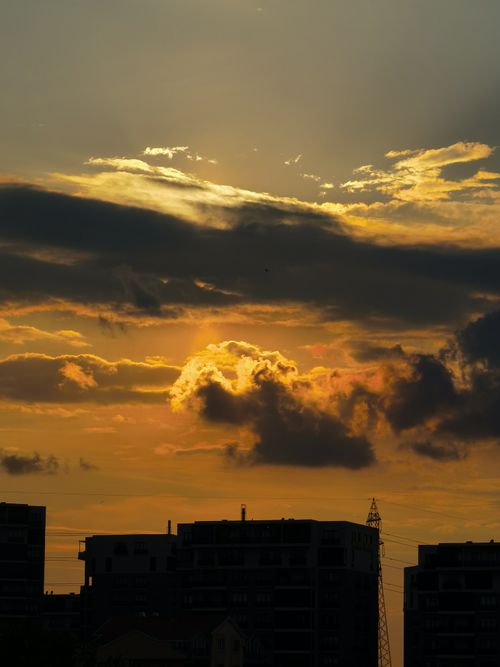 Free Silhouette of buildings under a striking golden hour sky, featuring dramatic clouds. Stock Photo