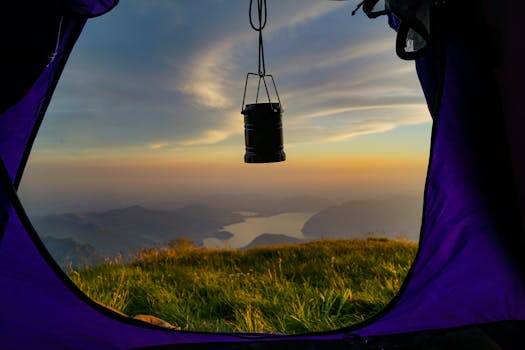 View of a scenic lake and mountains from a tent during sunrise, capturing adventure and nature's tranquility.