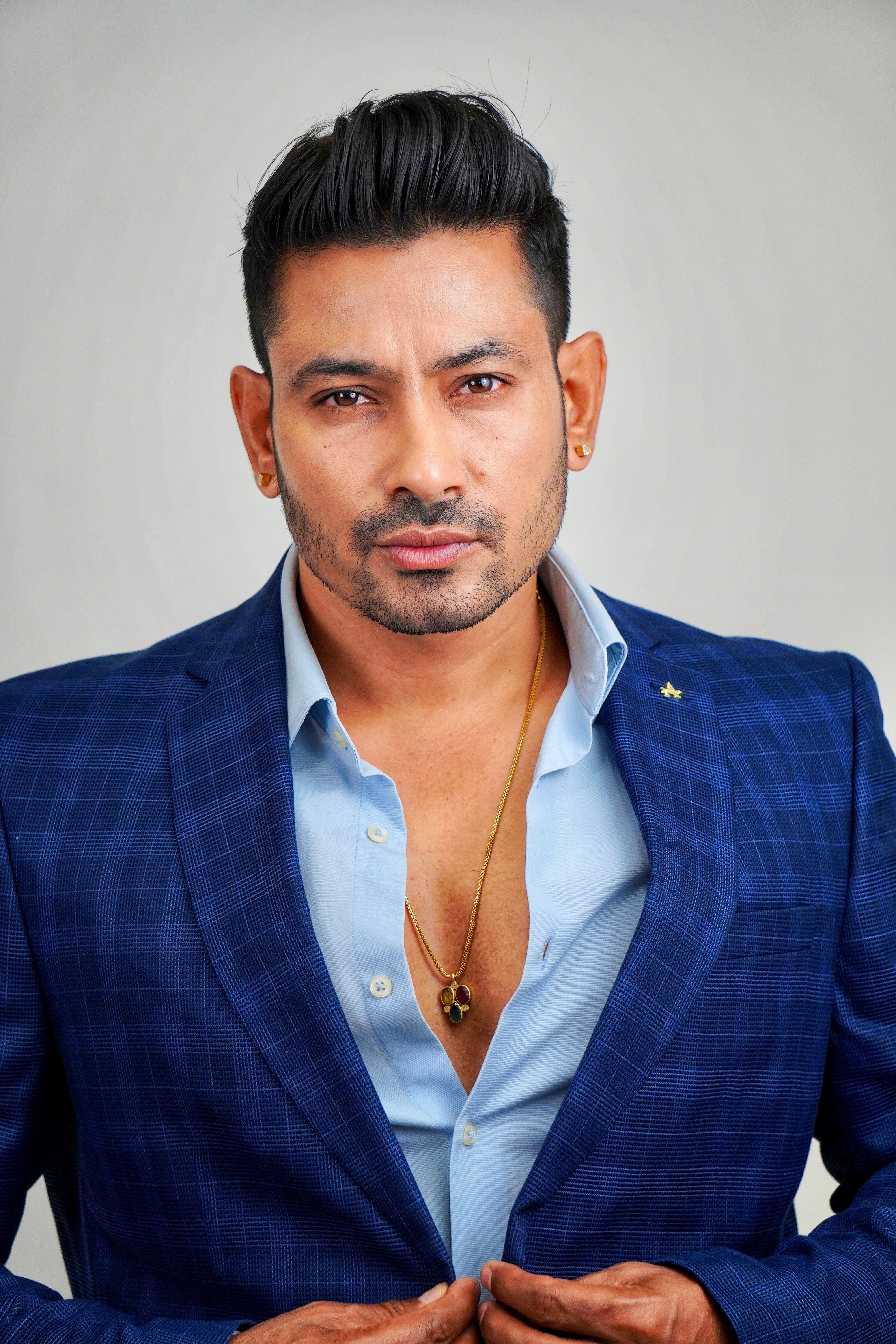 Elegant portrait of a man in a blue plaid suit with a confident expression, showcasing modern men's fashion.