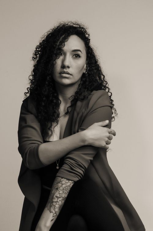 Free Artistic monochrome portrait featuring a woman with curly hair posing gracefully in a studio setting. Stock Photo