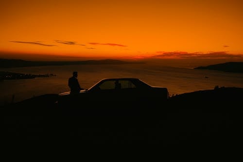 Man with Car on Sea Shore at Dusk