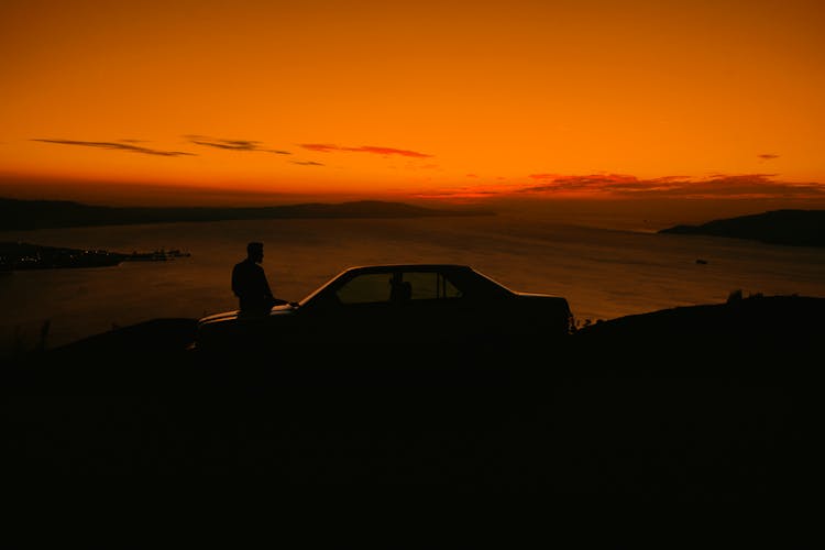 Man With Car On Sea Shore At Dusk