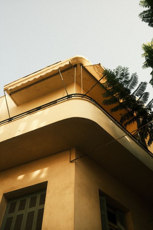Free Low angle view of an art deco building balcony with green plants, under a clear blue sky. Stock Photo