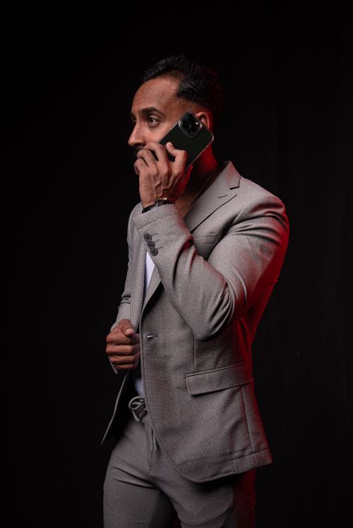 Free A stylish man in a gray suit talks on his phone against a dark background. Stock Photo