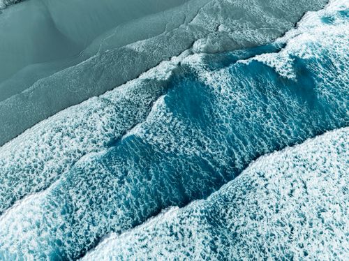 Free Dynamic aerial shot of crashing waves on Padstow beach, capturing the ocean's vibrant hues and textures. Stock Photo