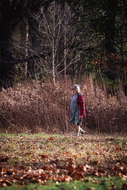 Free Elderly woman strolling through a serene forest in fall, showcasing nature's beauty. Stock Photo