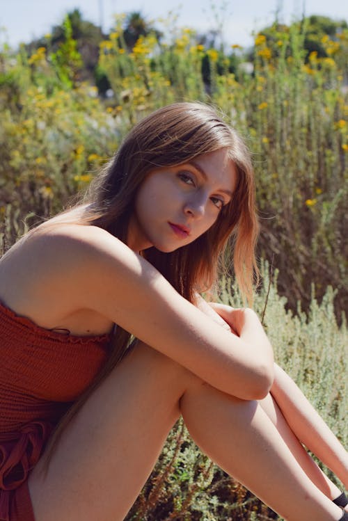 Woman in Red Tube Top Sitting on Green Grass