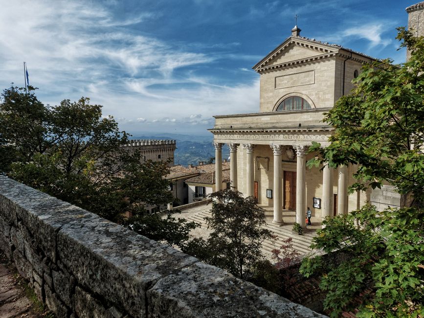 Scenic view of the Basilica in San Marino surrounded by trees on a sunny day.