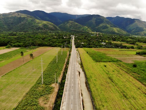 Aerial View of a Road Through the Green Valley Among the Fields