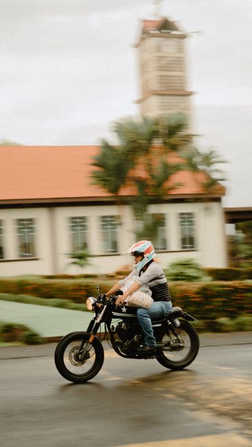 A motorcyclist wearing safety gear rides past buildings in La Fortuna, Costa Rica.