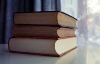 Three Piled Books on White Wooden Table