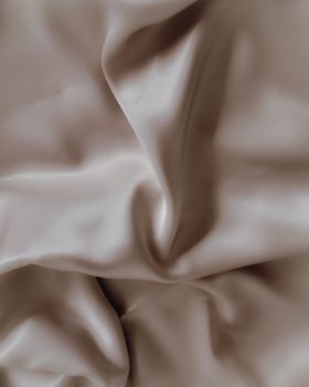 A close-up view of smooth beige satin fabric highlighting its soft, luxurious texture.