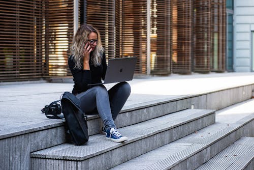 Free ノートパソコンを使用しながら階段に座っている女性 Stock Photo