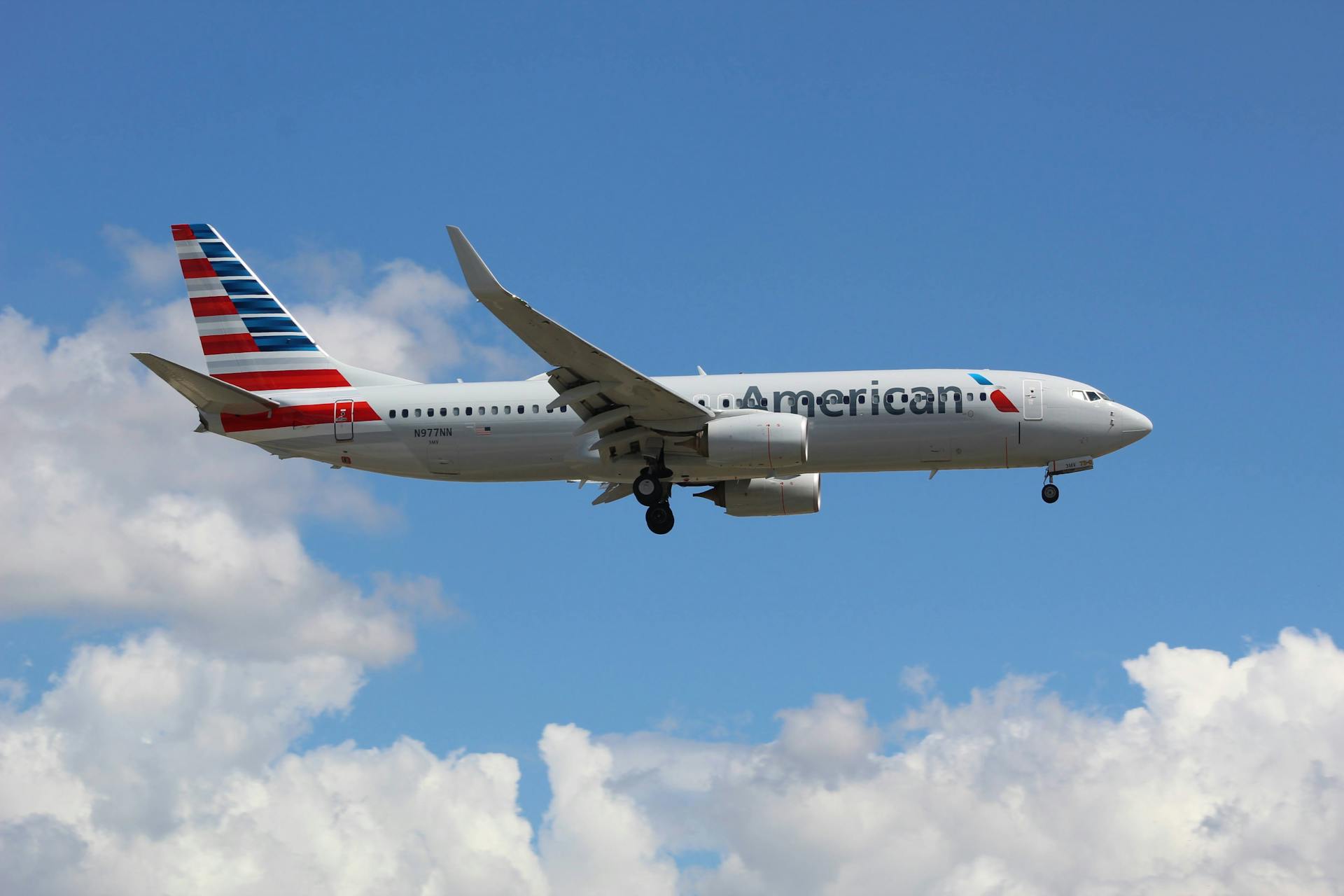 An American Airlines aircraft captured against a bright blue sky with clouds.