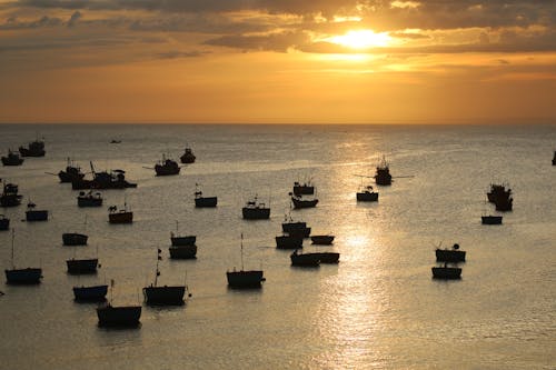 Silhouette of Boats on a Sea during Sunset